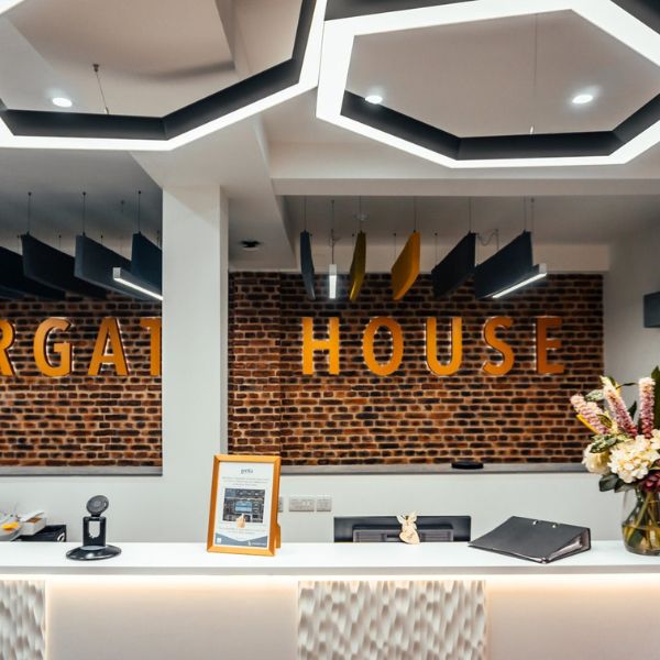 A custom dark-finish hexagon linear light fixture suspended over a premium retail display case, providing focused architectural illumination to highlight luxury products in a commercial showroom